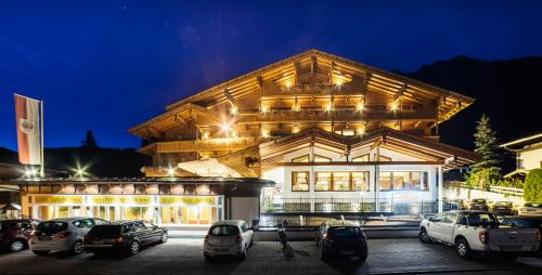 un gran edificio con coches estacionados frente a él en Hotel Alphof Alpbach, en Alpbach