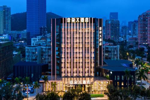 un edificio alto con un cartel en una ciudad en Atour X Hotel Zhuhai Lover Road Red Wave Bay Beach Seaview, en Zhuhai