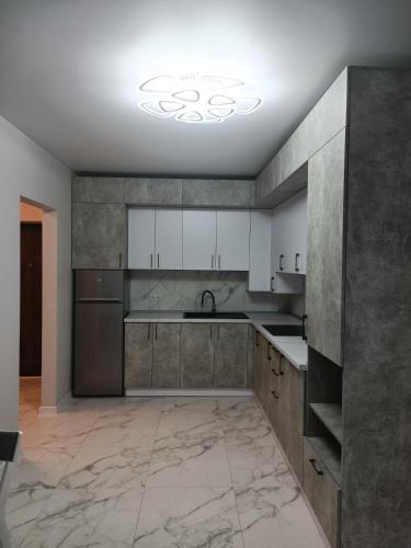 a kitchen with white cabinets and a marble floor at Apartments Domovik Myru St. 11s/21 in Mukacheve