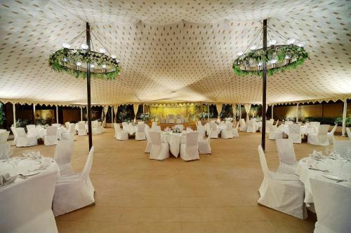 een grote kamer met witte tafels en stoelen en kroonluchters bij Hyatt Regency Amritsar in Amritsar