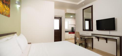 Dormitorio con cama, escritorio y TV en Centara Life Muscat Dunes Hotel, en Mascate