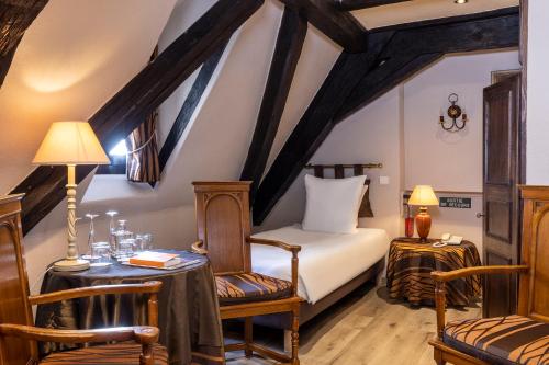 um quarto com uma cama, uma mesa e cadeiras em Hotel Restaurant Le Maréchal - Teritoria em Colmar