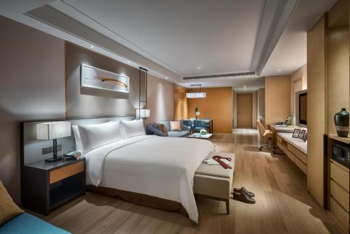 um quarto de hotel com uma cama grande e uma sala de estar em Primus Residence Shanghai Hongqiao em Xangai