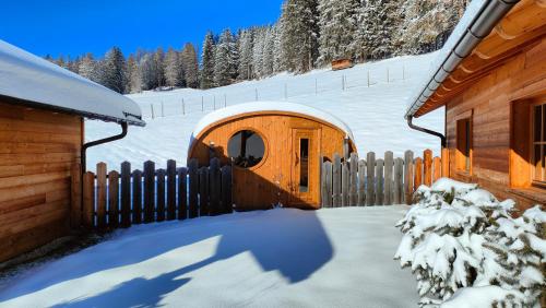 een houten huisje in de sneeuw met een hek bij Alpenchalets Mair in Sesto