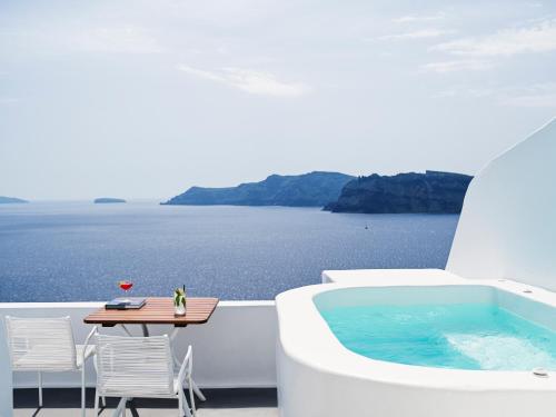 a balcony with a table and a swimming pool at Katikies Santorini - The Leading Hotels Of The World in Oia