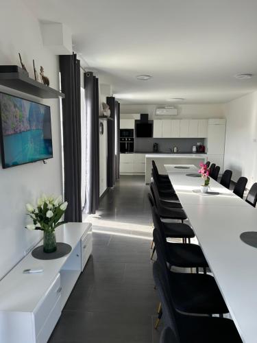 une salle à manger avec une grande table blanche et des chaises noires dans l'établissement Laura Apartmanház, à Mórahalom