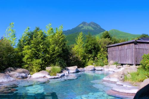 uma piscina de água com um edifício e montanhas ao fundo em Baien em Yufu