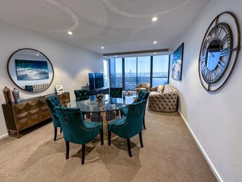 una sala da pranzo con tavolo, sedie e orologio di Deluxe 3 Bedroom Apartment in Southbank a Melbourne