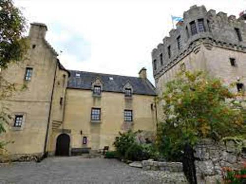 um grande edifício de pedra com uma árvore em frente em The Manor at Plane Castle em Falkirk