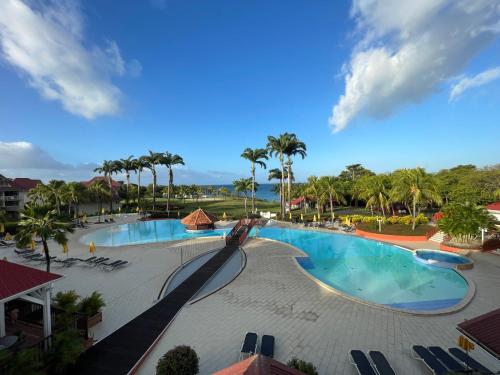 - une vue sur la piscine d'un complexe avec des palmiers dans l'établissement Appartement Madinina 6 personnes vue sur mer dans village vacances, à Sainte-Luce