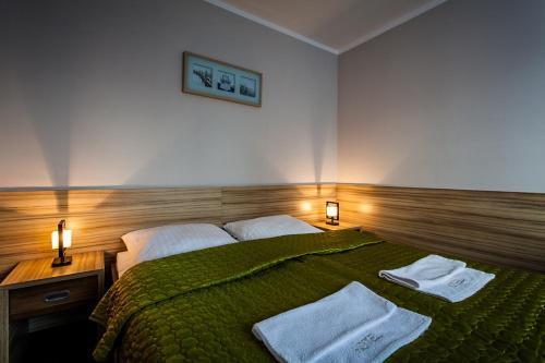 a bedroom with a green bed with towels on it at Hotel Alpex in Zabrze