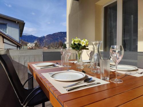 un tavolo in legno con piatti e bicchieri da vino su un balcone di Hubel Apartment 14 a Wilderswil