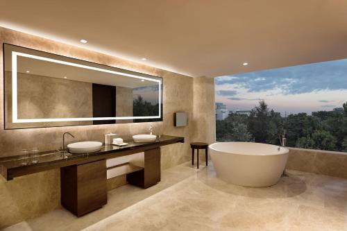 un bagno con due lavandini e una vasca e una grande finestra di Sheraton Grand Bengaluru Whitefield Hotel & Convention Center a Bangalore