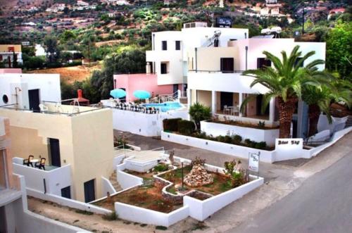 un gran edificio blanco con una palmera delante en Blue Sky Hotel Apartments, en Tolo