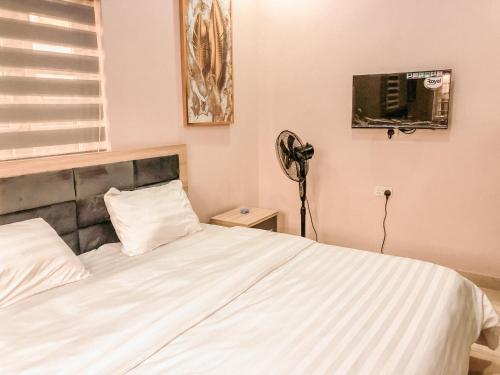 Schlafzimmer mit einem weißen Bett und einem Ventilator in der Unterkunft Crayford Homes in Ikeja