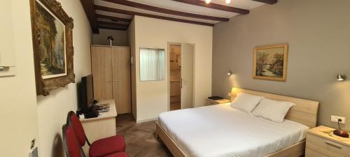 a bedroom with a white bed and a red chair at Alliance Hotel Ieper Centrum in Ypres