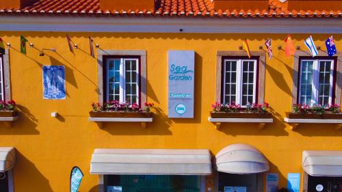 un bâtiment jaune avec des fenêtres et des drapeaux. dans l'établissement Sea Garden Peniche, à Peniche