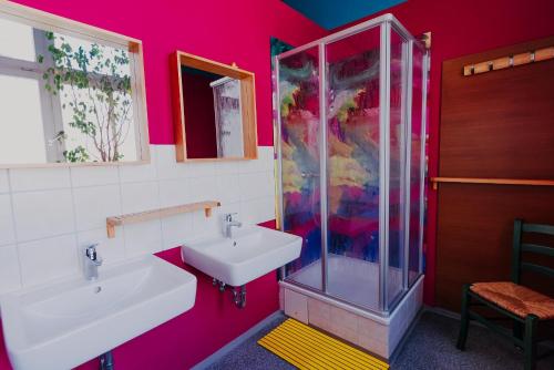 La salle de bains rose est pourvue d'un lavabo et d'une douche. dans l'établissement LaLeLu Hostel Dresden, à Dresde