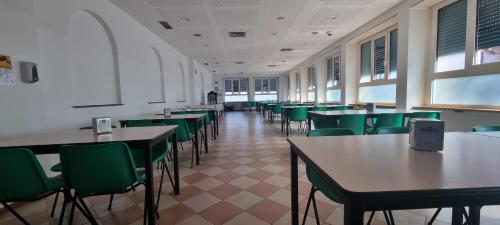 una clase con mesas y sillas verdes en una habitación en Ostello Giovane Europa di Trento, en Trento