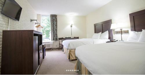 a hotel room with two beds and a flat screen tv at Inns of Virginia Arlington in Arlington