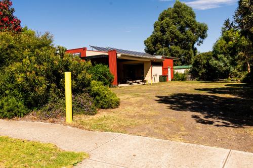 a red house with a yellow pole in front of it at Bellarine Lodge Sleeps 30 in Drysdale