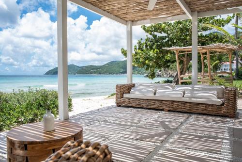 un porche con sofá y mesa y la playa en Long Bay Beach Resort, en Tortola Island