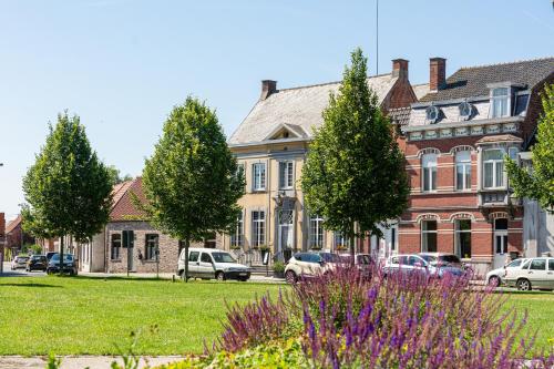 een groot bakstenen gebouw met auto's geparkeerd voor het bij Boutique hotel Sies in Watervliet