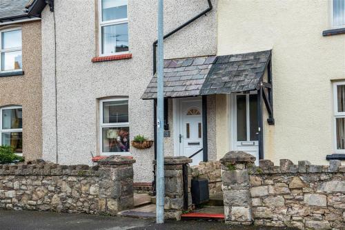 een huis met een stenen muur en een witte deur bij Lavender Terrace in Llandudno