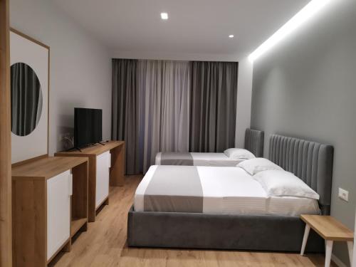 een slaapkamer met 2 bedden en een flatscreen-tv bij Te Aldo Hotel in Durrës