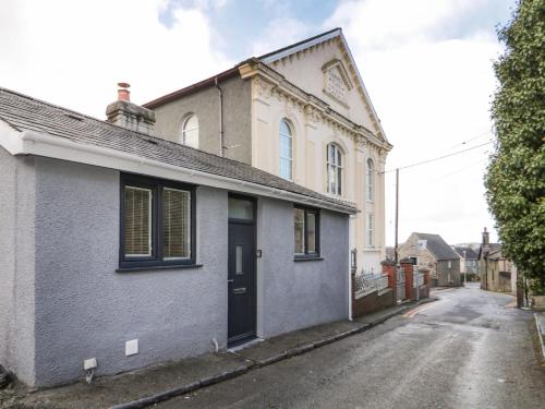 a white house with a black door on a street at Tŷ Capel Bach in Bangor