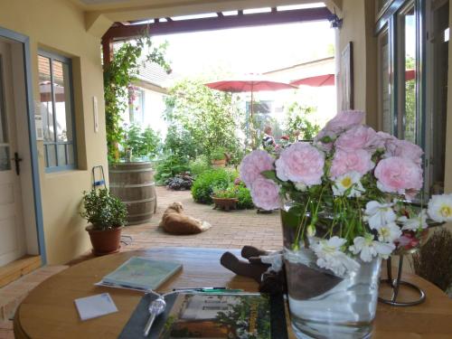 un tavolo con un vaso pieno di fiori rosa e bianchi di Stieglerhof Apartments Dr Eitner GnbR Bernd und Edeltrud a Illmitz