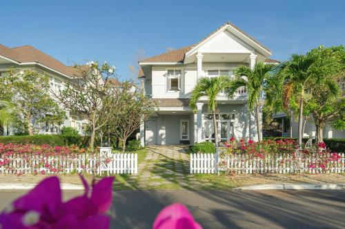 ein Haus mit einem weißen Gartenzaun und Blumen in der Unterkunft Casa Villa - Ocean View - Sealinks City Resort in Phan Thiet