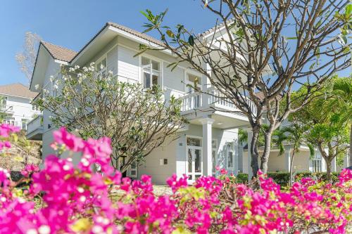 ein weißes Haus mit rosa Blumen davor in der Unterkunft Casa Villa - Ocean View - Sealinks City Resort in Phan Thiet