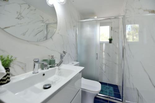 Baño blanco con aseo y lavamanos en Olivo II Luxury Apartment, en Hydra