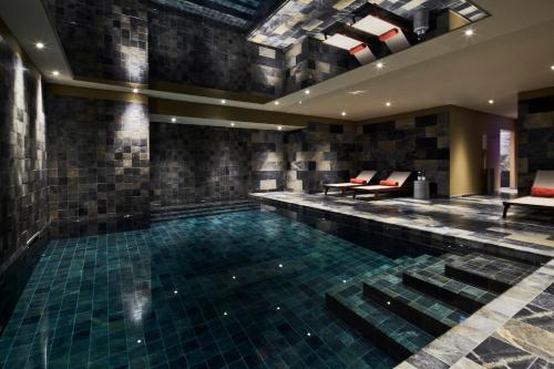 uma piscina num edifício com cadeiras vermelhas em La Licorne Hotel & Spa Troyes MGallery em Troyes