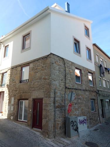 un edificio de piedra con una puerta roja en una calle en Ritta´s House - Covilhã, en Covilhã