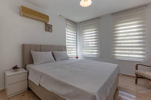 1 dormitorio con 1 cama blanca grande y ventanas en Güneş Villa, en Antalya