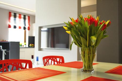 un jarrón de flores rojas y amarillas sentado en una mesa en Apartament Sopocka Przystań, en Sopot