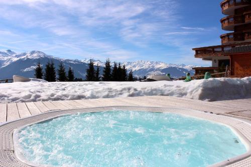 een hot tub op een patio met met sneeuw bedekte bergen bij Boutique Hotel Art de Vivre & SPA in Crans-Montana