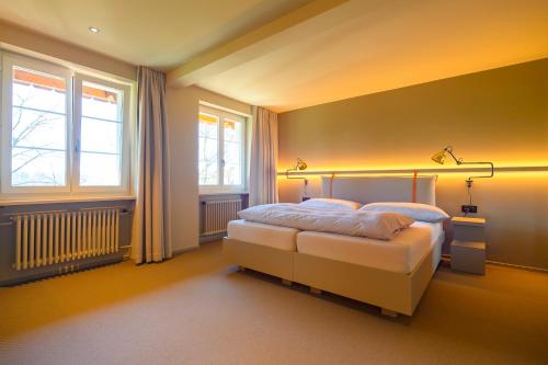 a bedroom with a bed and two windows at Landhotel Linde Fislisbach in Baden