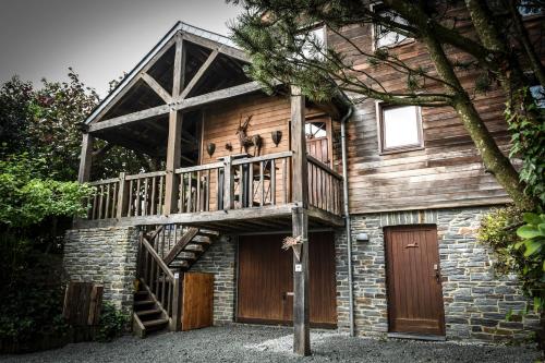 Cette grande maison en bois possède un balcon. dans l'établissement Saint-Hubert d'Ardenne, à Hatrival