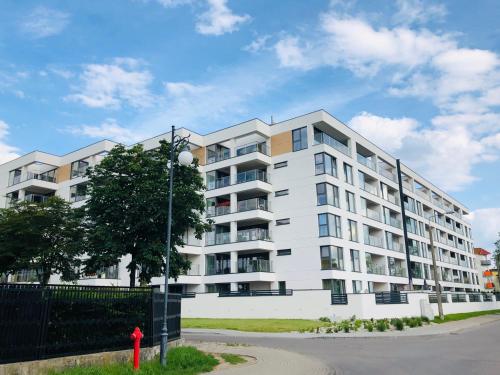 ein weißes Apartmenthaus mit einem roten Hydranten davor in der Unterkunft Apartament Złota Brama in Lyck