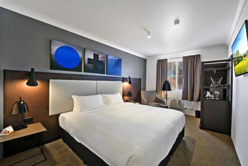 een hotelkamer met een groot wit bed en een bureau bij Silkari Urban CKS Sydney Airport Hotel in Sydney