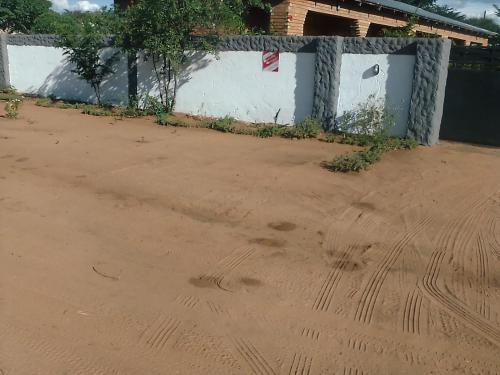 a dirt floor with footprints in front of a fence at Sunshinevibe guest house in Kasane