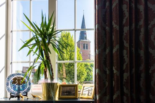 een raam met een potplant en een kerk bij Boutique hotel Sies in Watervliet