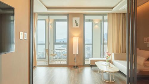 sala de estar con sofá, mesa y algunas ventanas en Elbon The Stay, en Busan