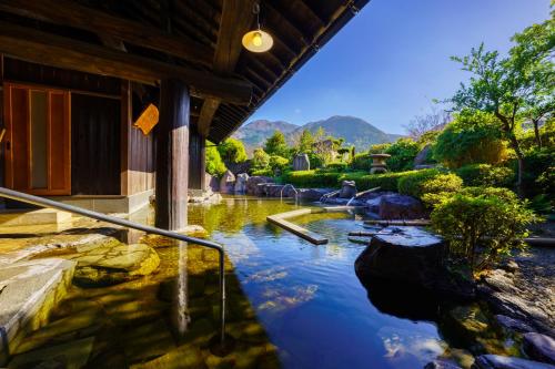 een zwembad met water naast een gebouw met bergen op de achtergrond bij 由布の里 旅荘 牧場の家 Ryoso Makibanoie in Yufu