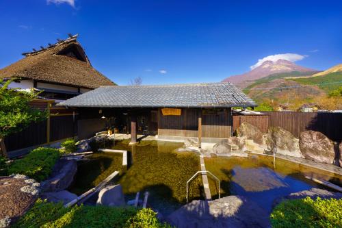 een huis met een vijver voor een berg bij 由布の里 旅荘 牧場の家 Ryoso Makibanoie in Yufu