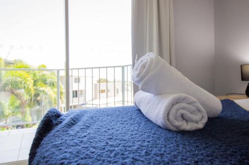 a towel animal sitting on a bed with a window at Caloundra Central Apartment Hotel Official in Caloundra