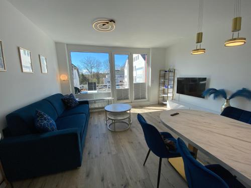 ein Wohnzimmer mit einem blauen Sofa und einem Tisch in der Unterkunft Modernes Apartment an Timmendorfer Promenade, 1. Reihe in Timmendorfer Strand